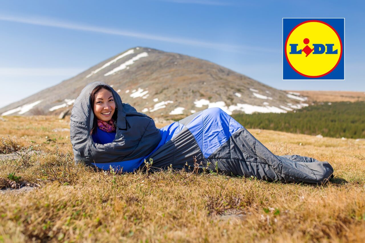 Frau liegt in einem Schlafsack auf der Wiese vor einem Berg, oben rechts ist das Logo von LIDL zu sehen