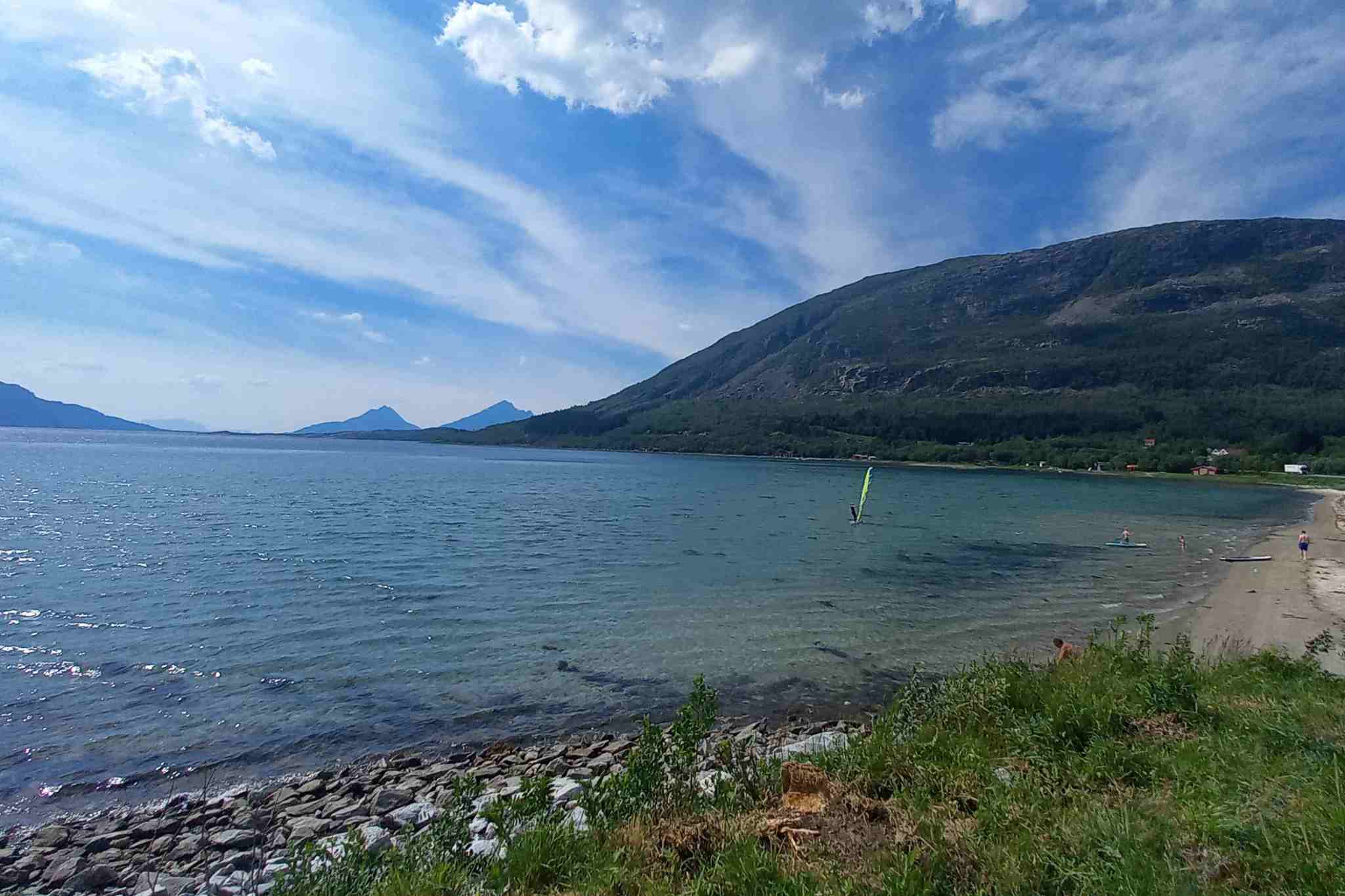 Bucht mit Sandstrand und Blick auf die umliegenden Berge direkt am Küstenweg.