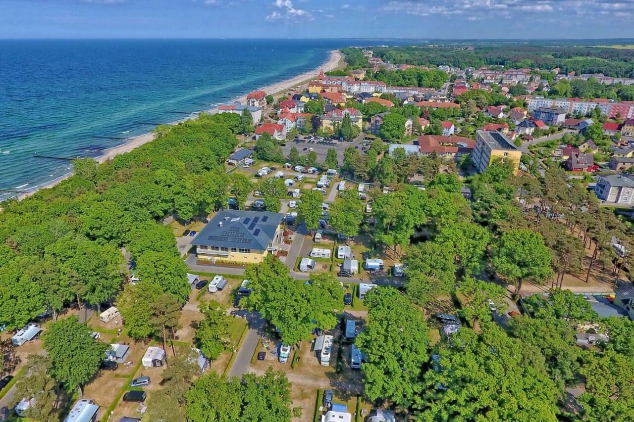 Camper-Paradiese: Deutschlands Top-Campingplätze, die man erlebt haben muss 2 Camping.info Nr. 1 in Deutschland: Campingplatz Kühlungsborn. Zu sehen ist eine Luftaufnahme von einem Campingplatz im Grünen, im Hintergrund das Meer.
