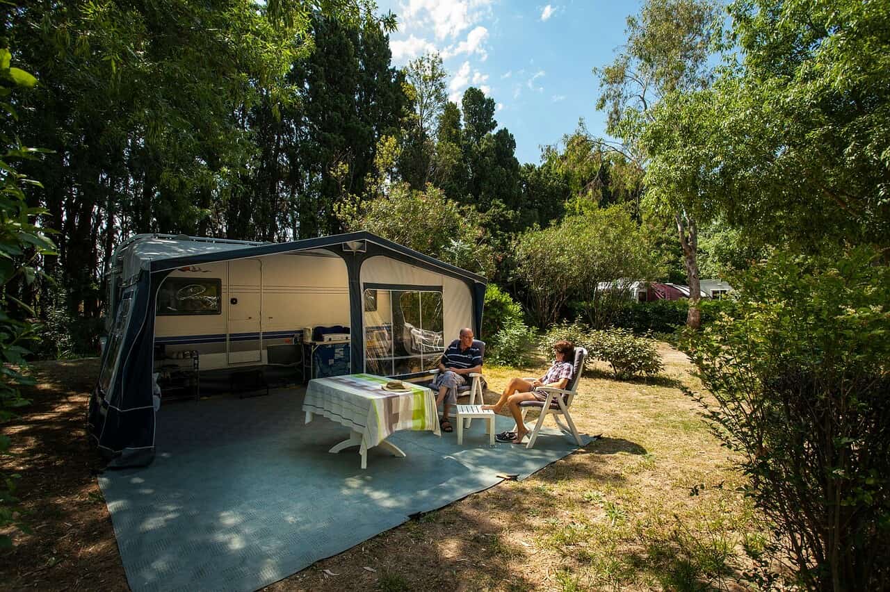 Camping Le Haras Wohnmobilstellplatz zwischen Baeumen auf dem Campingplatz