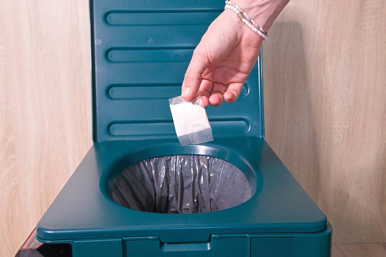 Nahaufnahme einer hand, die Kaffeepulver in einen kleinen Papierbeutel gibt.